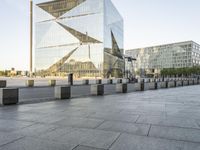 a very tall building on a busy street in europe with glass windows and concrete pillars