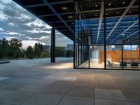 the large glass enclosed space features stone, steel and wood benches on the decking