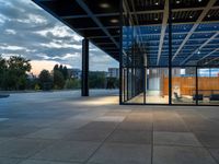 the large glass enclosed space features stone, steel and wood benches on the decking