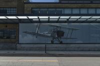 an airplane in front of a large advertisement on the building at a bus stop in london