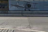 an airplane in front of a large advertisement on the building at a bus stop in london