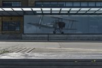 an airplane in front of a large advertisement on the building at a bus stop in london