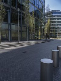 many white concrete pedestals are lined up on a bricked walkway near a tall building