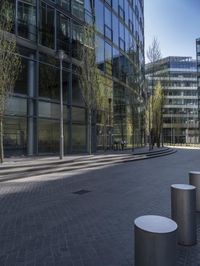 many white concrete pedestals are lined up on a bricked walkway near a tall building