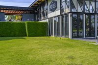 the glass walled patio and garden area has outdoor furniture on top of it with green hedges