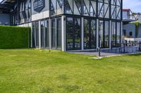 the glass walled patio and garden area has outdoor furniture on top of it with green hedges