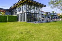 the glass walled patio and garden area has outdoor furniture on top of it with green hedges