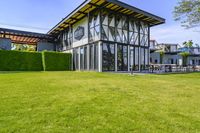 the glass walled patio and garden area has outdoor furniture on top of it with green hedges