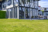 the glass walled patio and garden area has outdoor furniture on top of it with green hedges