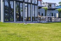 the glass walled patio and garden area has outdoor furniture on top of it with green hedges