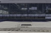 an empty parking lot with a parking meter in front of a large warehouse building with glass walls