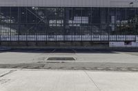 an empty parking lot with a parking meter in front of a large warehouse building with glass walls