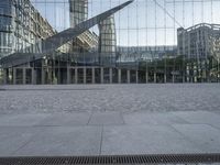 the giant pair of scissors are placed outside a glass building with buildings reflecting in it