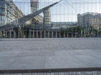 the giant pair of scissors are placed outside a glass building with buildings reflecting in it