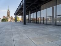 an empty courtyard area surrounded by windows and a clock tower in the distance with large buildings in the background