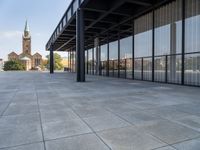 an empty courtyard area surrounded by windows and a clock tower in the distance with large buildings in the background