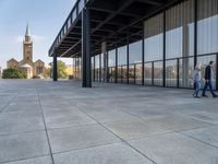 an empty courtyard area surrounded by windows and a clock tower in the distance with large buildings in the background