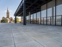 an empty courtyard area surrounded by windows and a clock tower in the distance with large buildings in the background