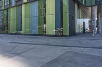 a bicycle locked to a post and in front of a green glass building with columns