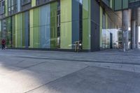 a bicycle locked to a post and in front of a green glass building with columns