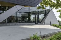 the rear of an office building with plants in front of it and a clock at the entrance