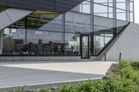 the rear of an office building with plants in front of it and a clock at the entrance