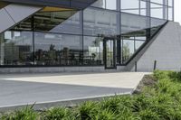 the rear of an office building with plants in front of it and a clock at the entrance