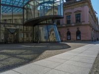 Glass Walls Reflecting Clear Skies on Cobblestone Roads