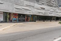 a very empty street in front of a museum and some building with glass windows, near a paved street