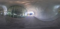 a view through a glassed tunnel looking into a pool and park area that is surrounded by a concrete wall