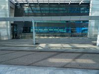 a bench sitting outside of a glassy building next to a staircase next to an entrance