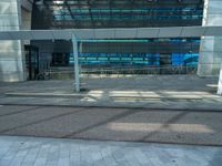 a bench sitting outside of a glassy building next to a staircase next to an entrance