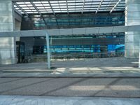 a bench sitting outside of a glassy building next to a staircase next to an entrance