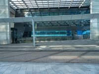 a bench sitting outside of a glassy building next to a staircase next to an entrance