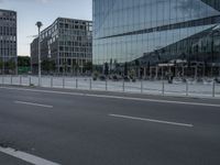 buildings in the background reflected in a glassy building window from a street corner near traffic