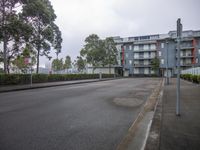 a paved street surrounded by buildings and a fenced in area along the side of the road