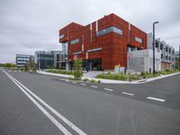 large orange colored building sitting next to an empty road on cloudy day with street light