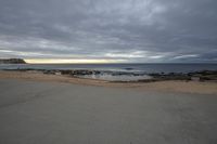 a man walking on the beach towards the ocean in an open space on a cloudy day