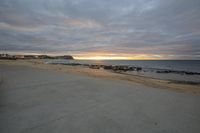 a man walking on the beach towards the ocean in an open space on a cloudy day