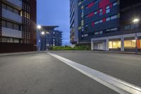 a paved street with high rise buildings at dusk in the background, with a row of parked motorcycles parked on the road