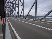 a truck is traveling on a bridge over water and land area with mountains in the background