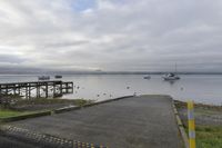 a dock with boats is empty and the water near it is very calm, with a few boats on the water