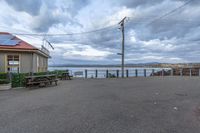 a bench on a road with a sky background and some water in the back ground