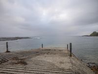 an empty boat dock is under cloudy skies over the sea water at low tide point