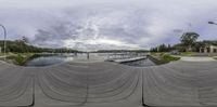 fisheye view of a river and boat dock and some buildings with a bridge in the distance