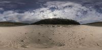 a photograph of a sand and trees area under a cloudy sky and clouds above it