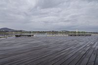 there is a wooden pier with benches on it and water in the background under a cloudy sky