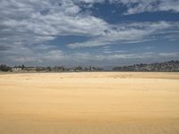 there is a lone person on a beach with the sky and clouds in the background