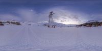 the sky is covered in clouds and is seen through snowshoe tracks of a ski lift