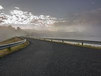 a curving road with a fog covered sky in the background and trees on the edge